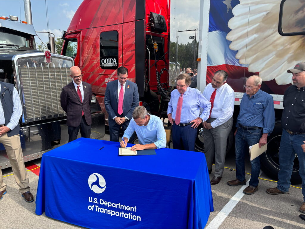 USDOT Secretary Sean P. Duffy signing an order at a trucking event in Austin announcing stronger English language enforcement guidelines for commercial truck drivers.
